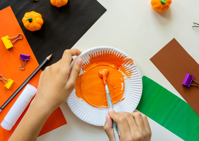 student painting a plate orange to create a pumpkin for halloween